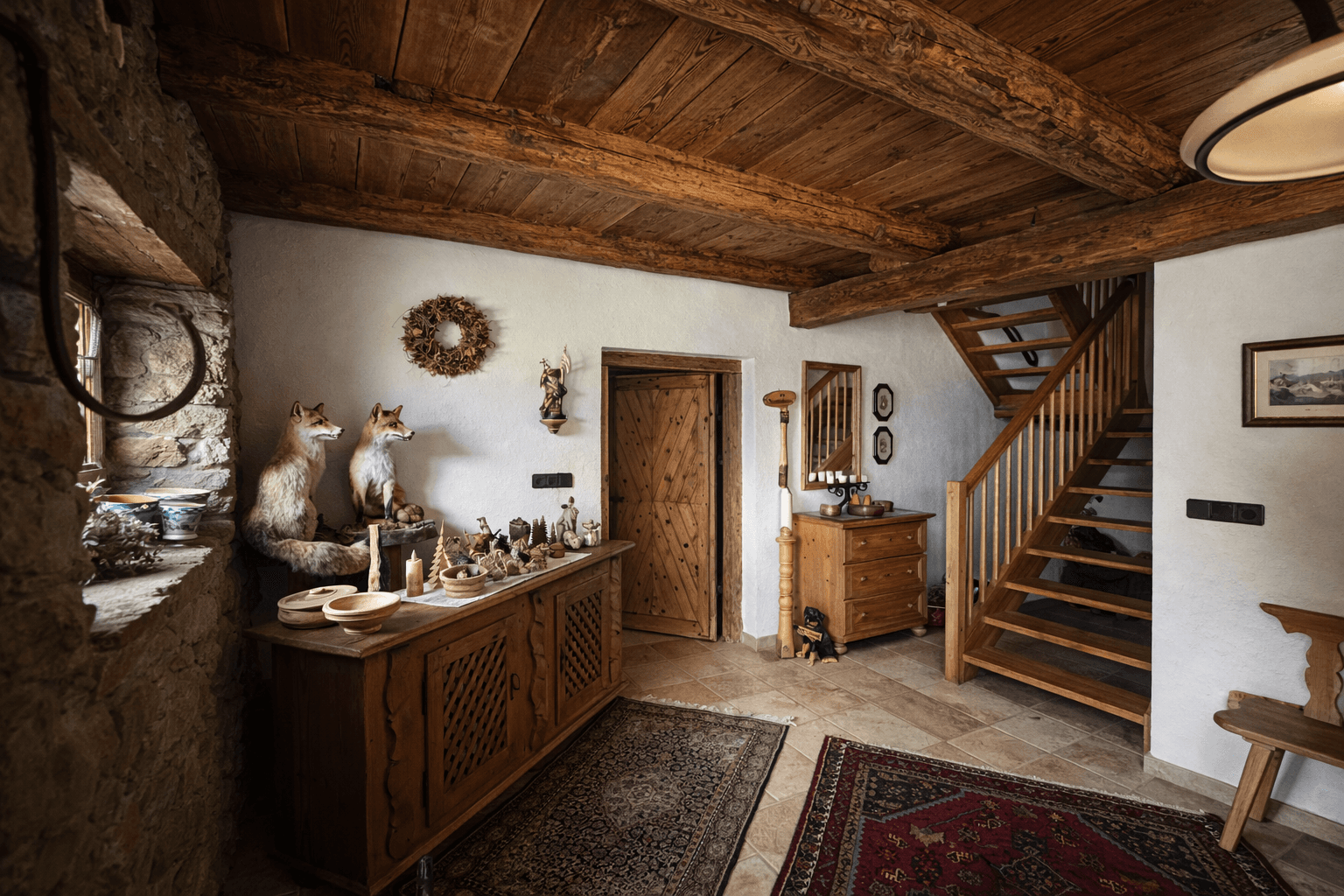 Rustikaler Eingangsbereich mit Holztreppe, Holzbalkendecke und traditioneller Dekoration.