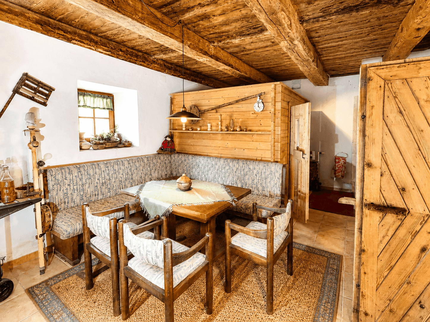 Traditioneller Essbereich mit Eckbank, Holztisch und sichtbaren Deckenbalken in rustikalem Stil.
