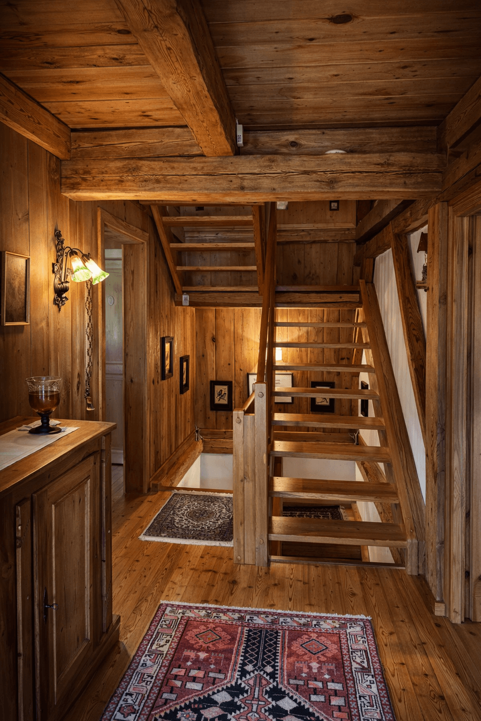 Rustikaler Flur mit Holztäfelung, Holzbalkendecke und einer offenen Holztreppe.