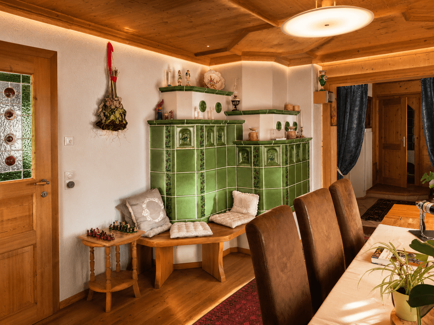 Essbereich mit traditionellem Kachelofen, Holzboden und rustikalen Möbeln.