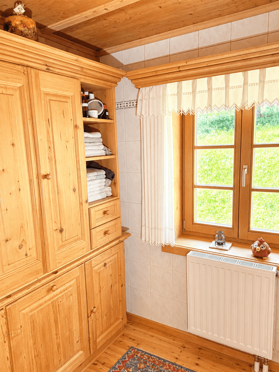 Geräumiger Holzschrank in einem Badezimmer mit Fenster und Heizkörper.