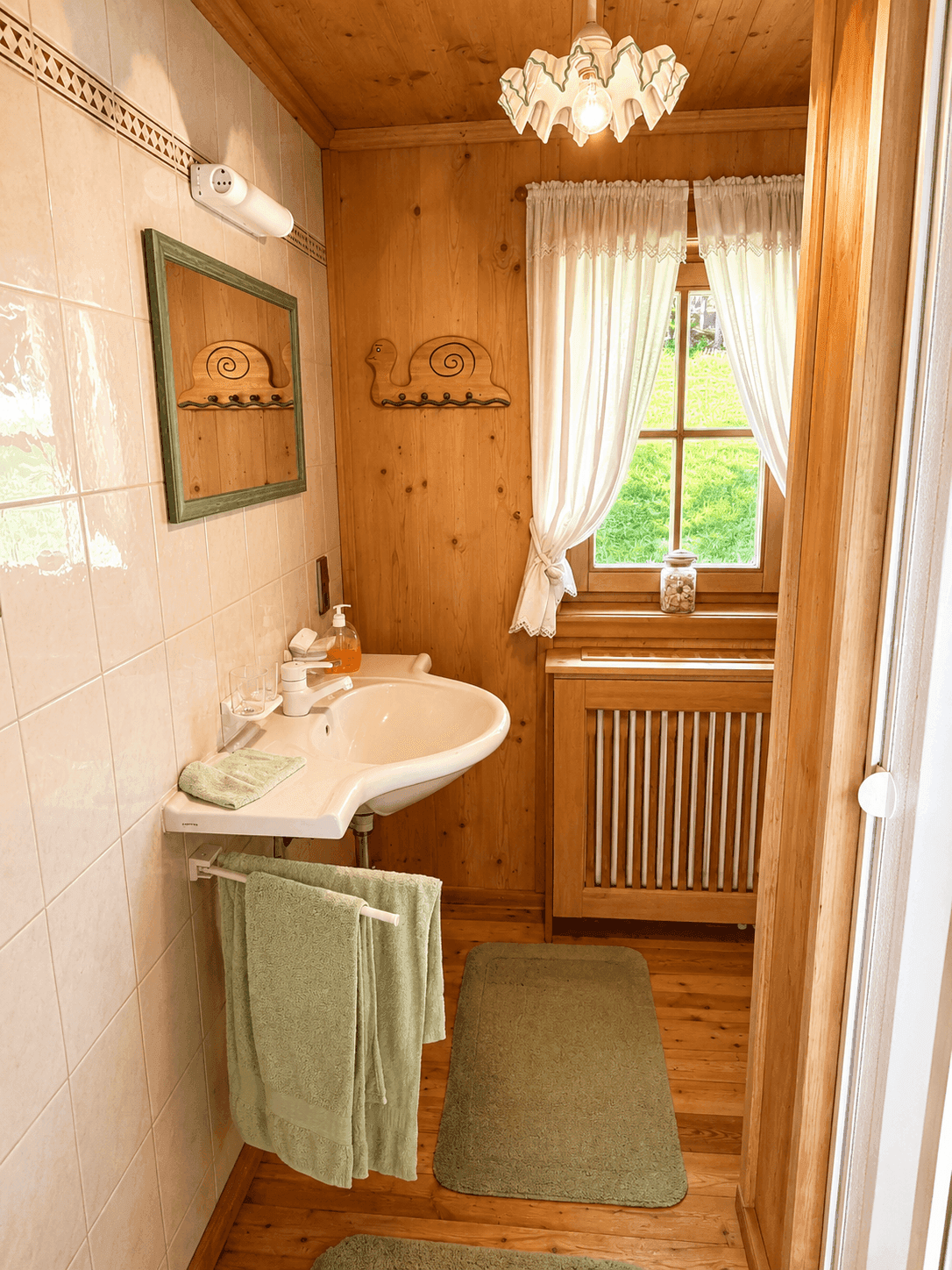 Kleines Badezimmer mit Einzelwaschbecken, Holzvertäfelung und Fenster mit Vorhängen.