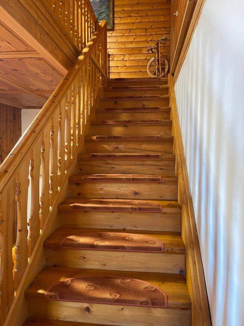 Holztreppe mit Teppichläufern und Holztäfelung, die zu den oberen Etagen führt.