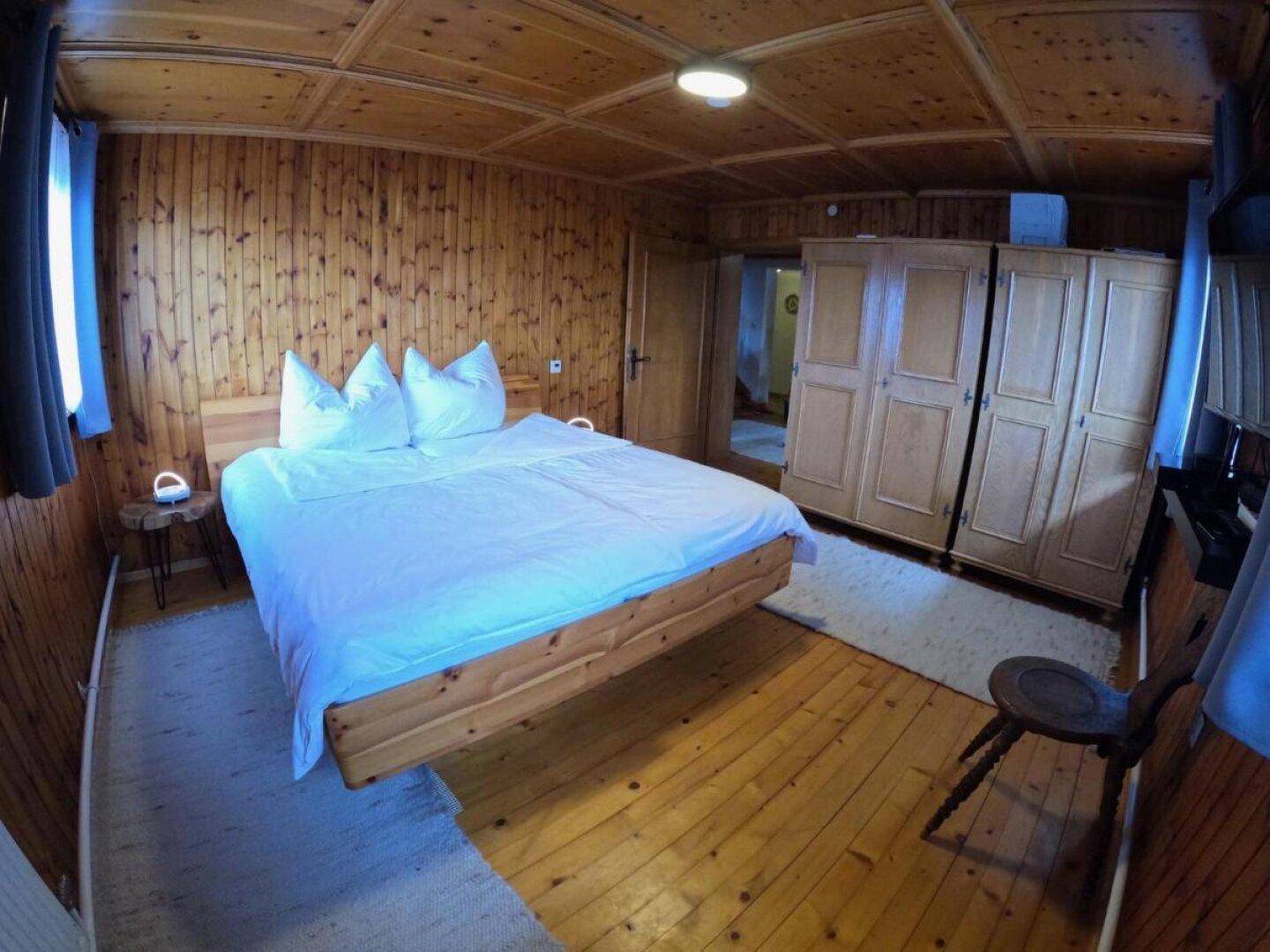 Gemütliches Schlafzimmer mit Holzboden, Holztäfelung und einem Doppelbett.