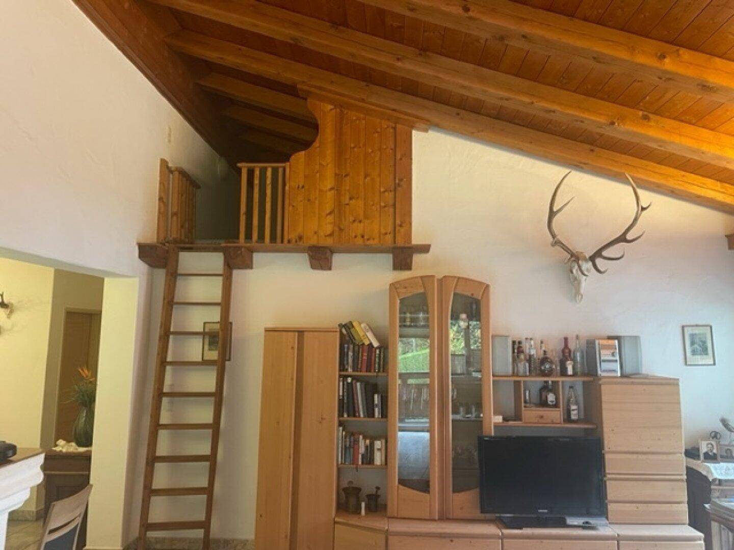 Wohnzimmer mit hoher Holzbalkendecke, Galerie und traditioneller Dekoration.