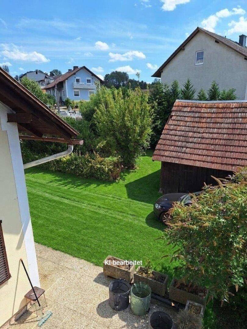 Blick auf einen gepflegten Rasen und ein traditionelles Haus mit Ziegeldach in sonniger Lage.