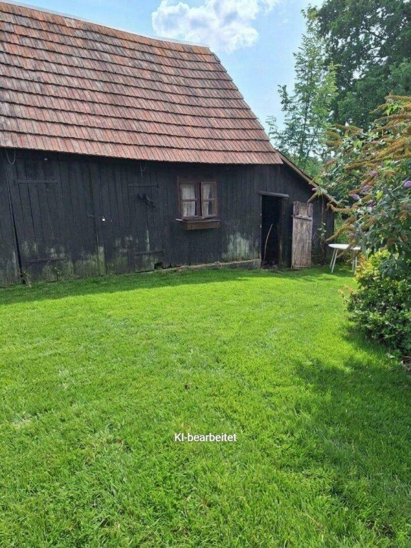 Rustikales Holzgebäude mit rotem Ziegeldach und grüner Rasenfläche im Garten.
