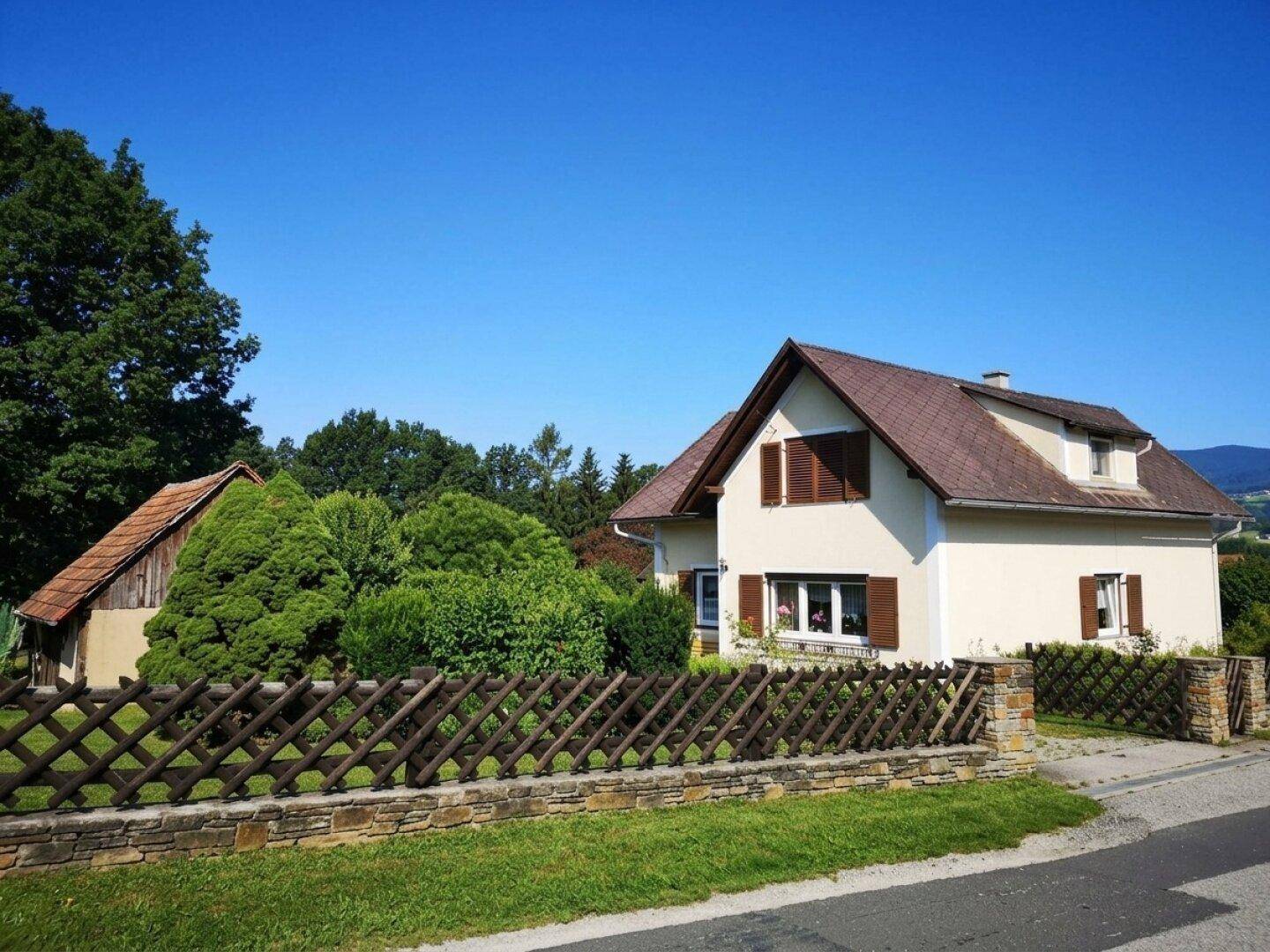 Charmantes Einfamilienhaus mit Satteldach und Holzzaun in ländlicher Umgebung.