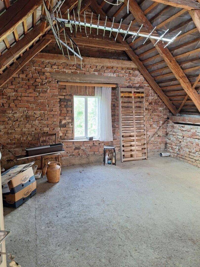 Unausgebauter Dachboden mit freiliegenden Ziegelwänden und Holzbalken.