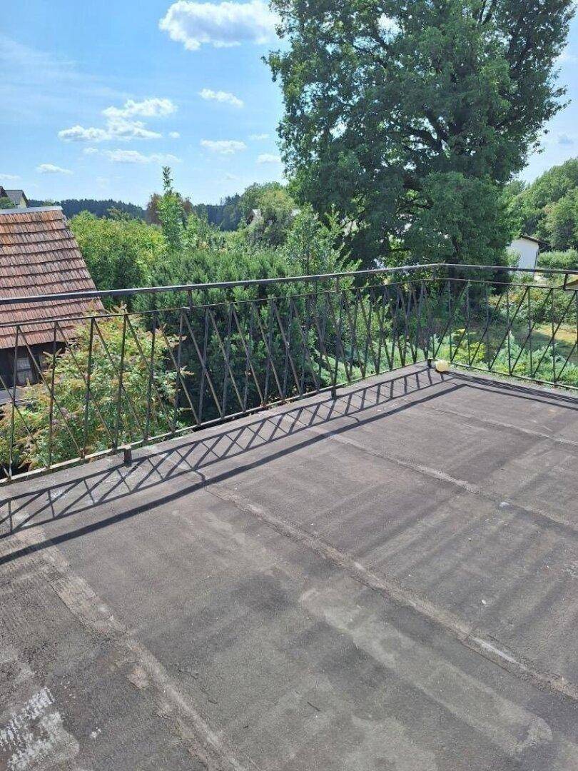 Weitläufige Dachterrasse mit Metallgeländer und Panoramablick über die Landschaft.
