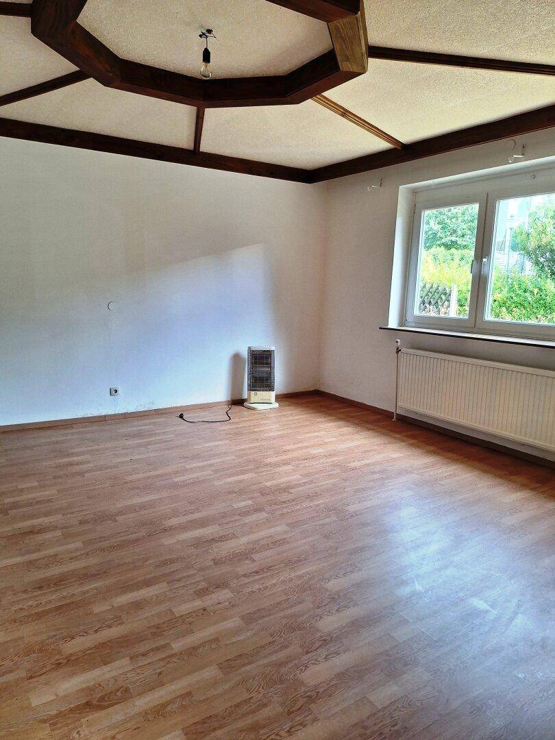 Leerer Raum mit Laminatboden und einer dekorativen Holzdeckenkonstruktion, die Charakter verleiht.