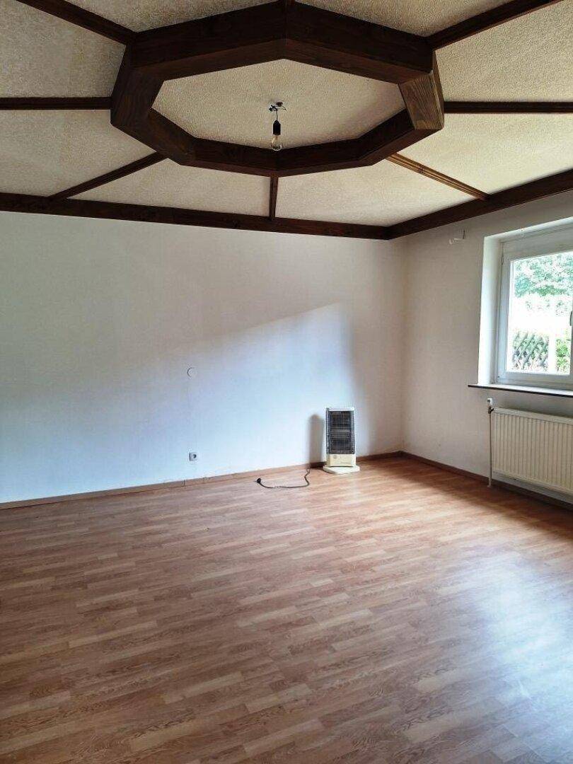 Geräumiger Raum mit Laminatboden und einer auffälligen Holzdeckenkonstruktion, die den Raum prägt.