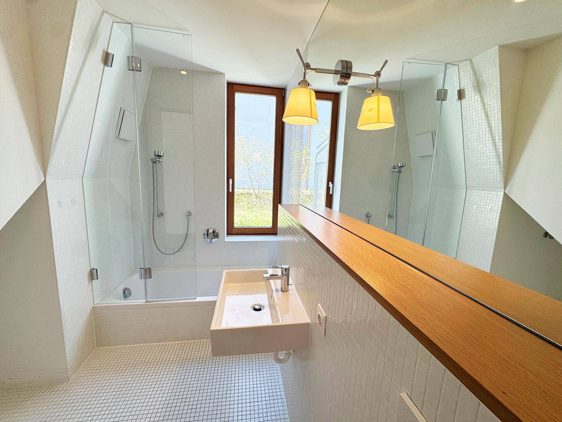 Modernes Badezimmer mit Badewanne, Duschabtrennung aus Glas und großem Spiegel.