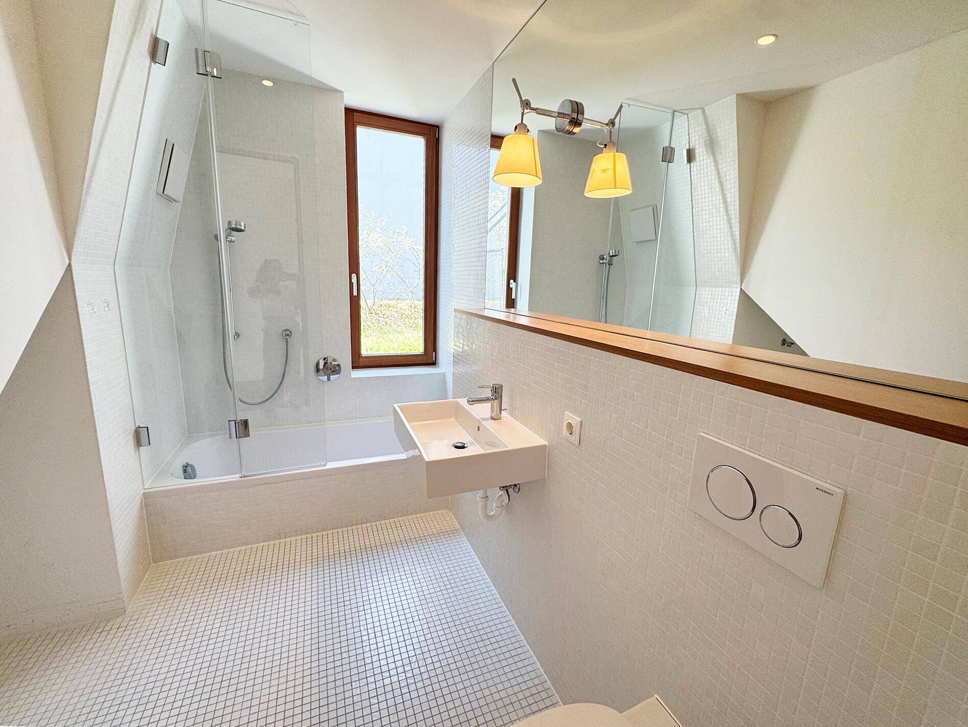 Helles Badezimmer mit Badewanne, Duschbereich, modernem Waschbecken und Fenster.