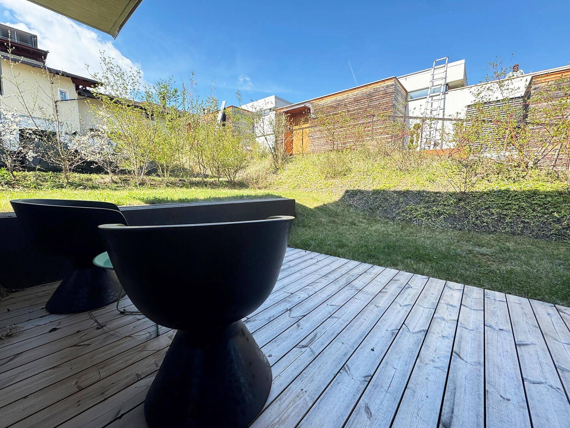 Gemütliche Holzterrasse mit modernen Sitzgelegenheiten und Blick in den grünen Gartenbereich.