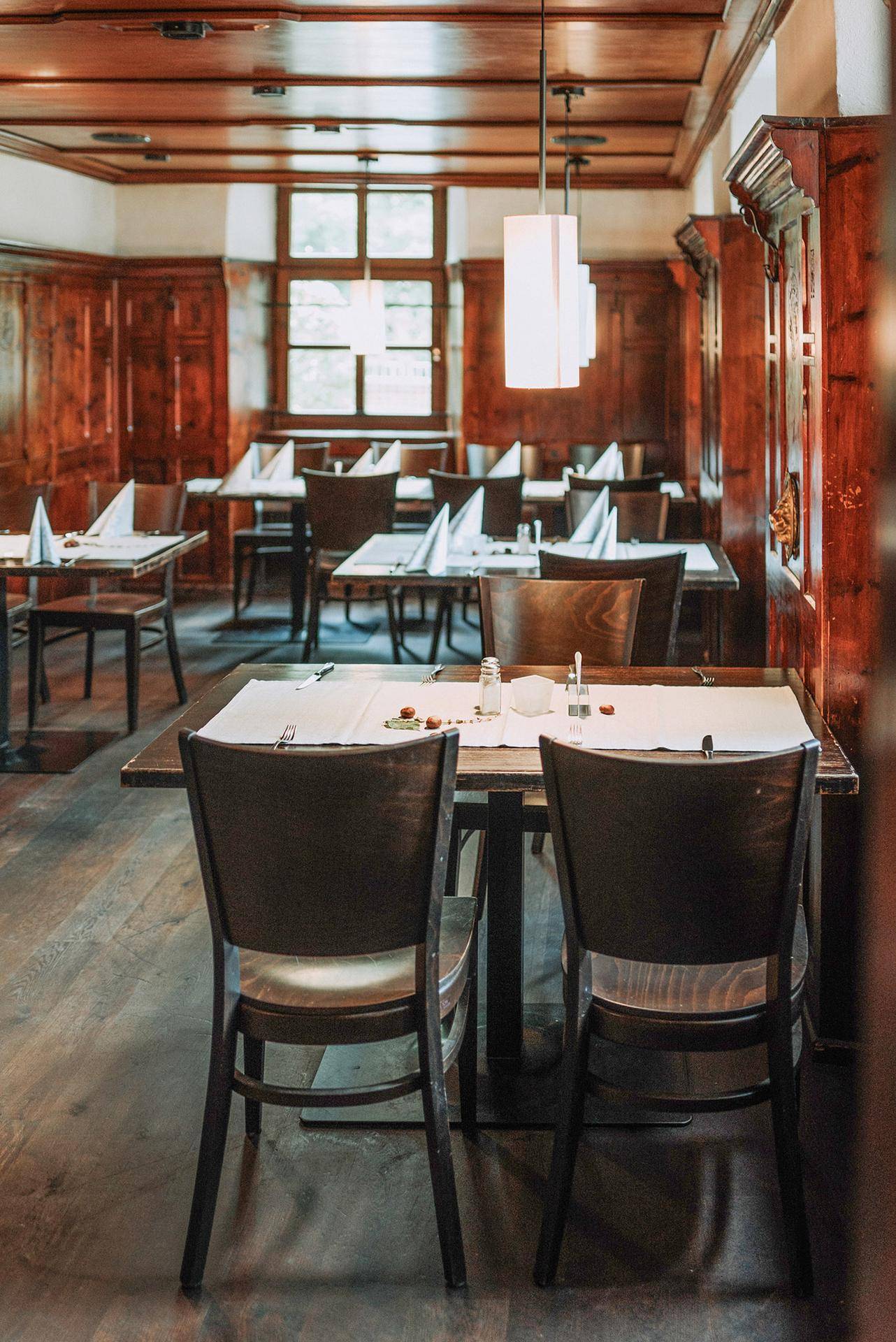 Traditioneller Restaurantraum mit dunkler Holzvertäfelung, Holzböden und elegant gedeckten Tischen.