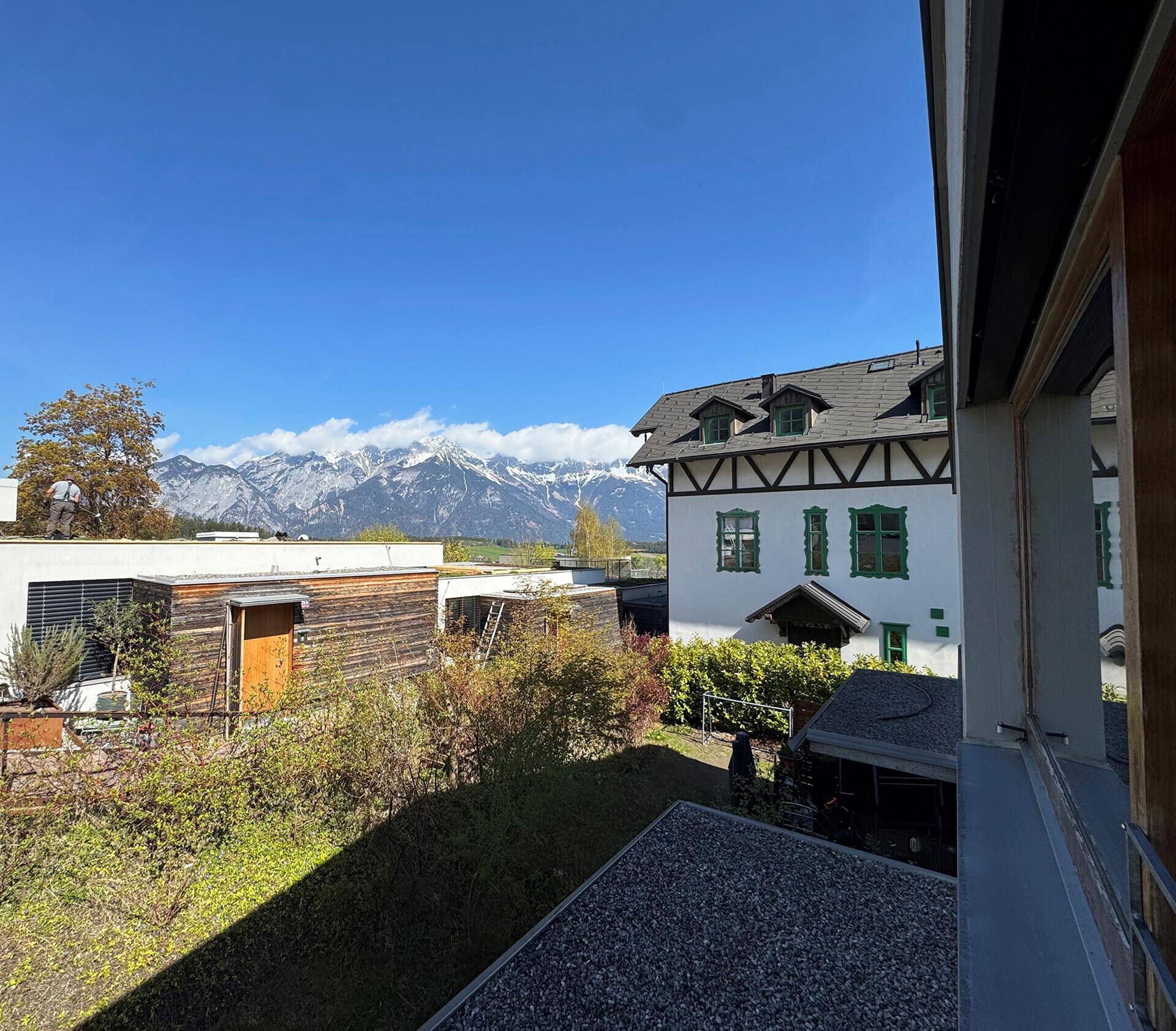 Panoramablick von einem Balkon auf die schneebedeckten Berge und die umliegende Bebauung.