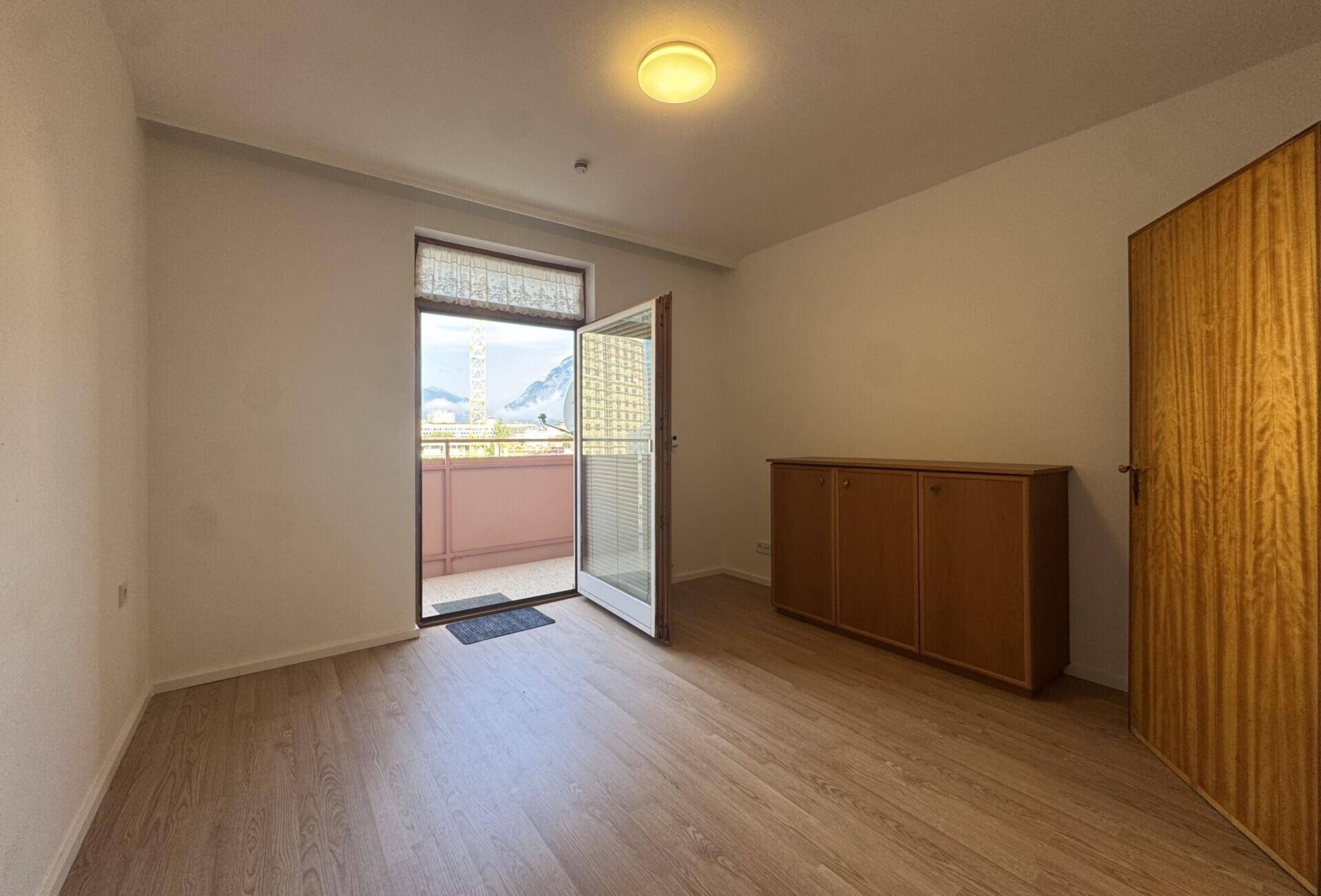 Geräumiger Raum mit Holzboden und direktem Zugang zu einem Balkon, bietet Bergblick.
