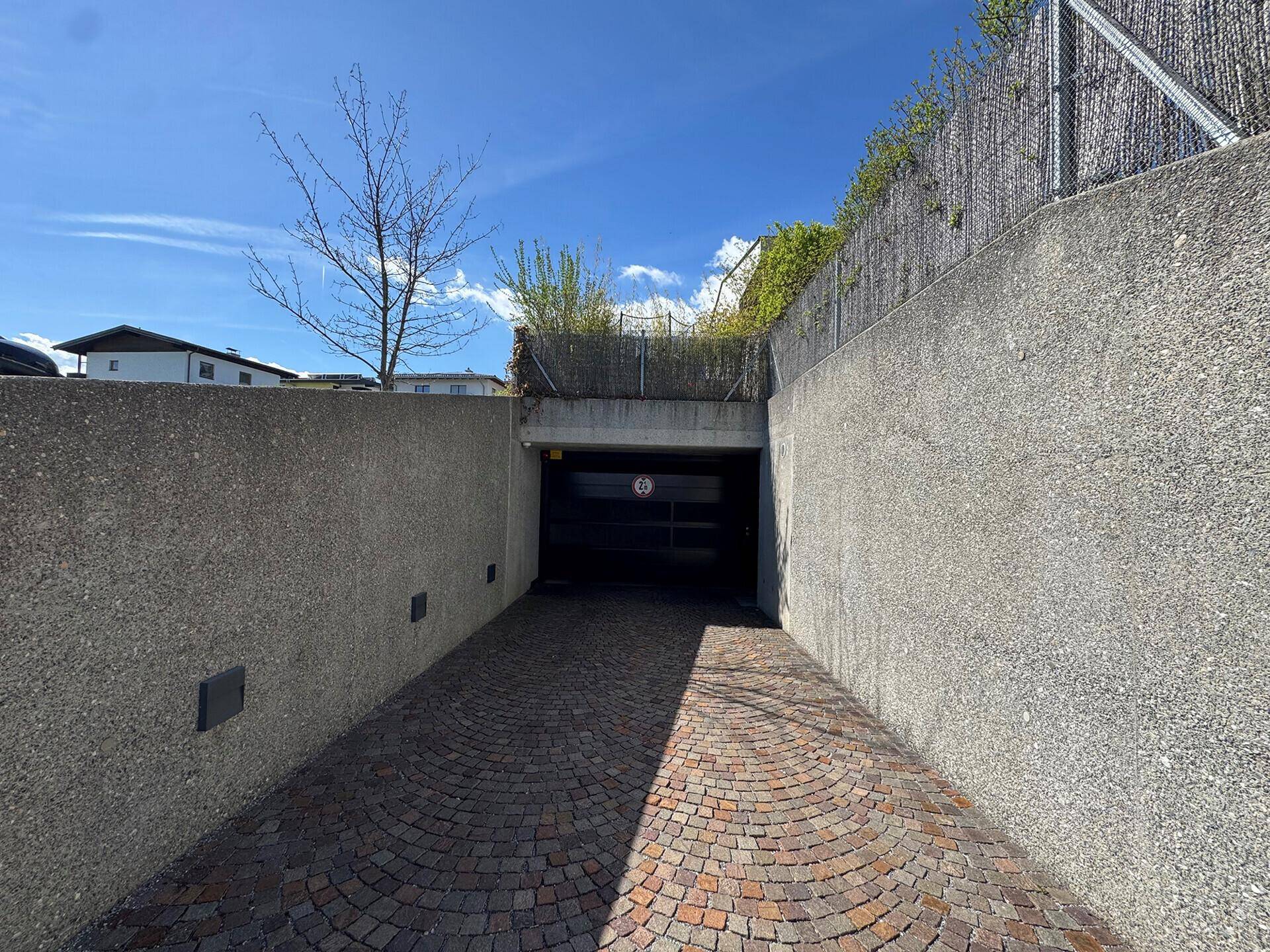 Einfahrt zur Tiefgarage mit Betonwänden und einem geschlossenen Garagentor.