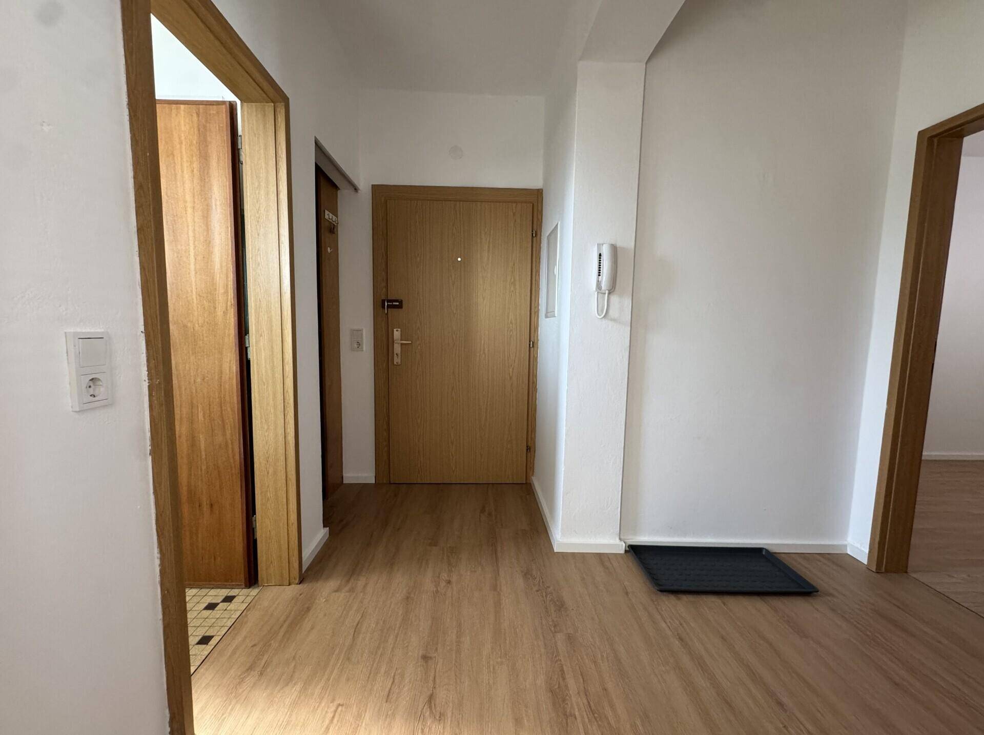 Eingangsbereich mit Holztür und hellem Holzfußboden, bietet einen freundlichen Empfang.