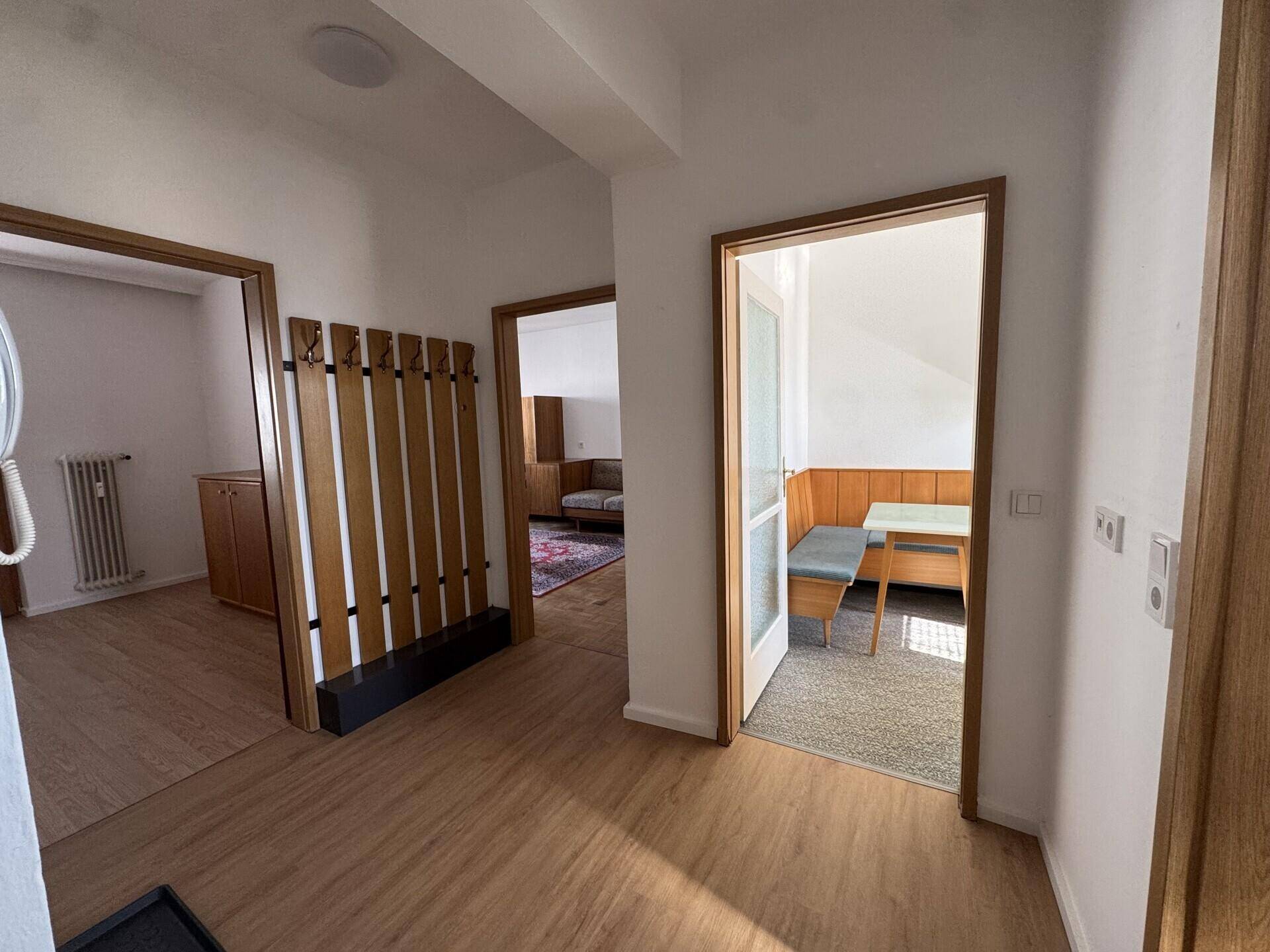Heller Flur mit Holzfußboden und Garderobe, verbindet die verschiedenen Räume der Wohnung.