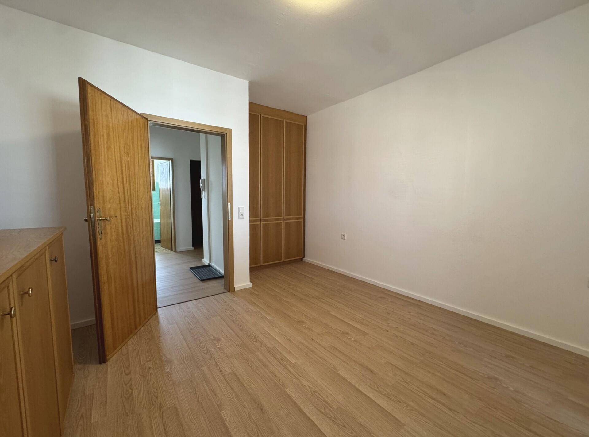 Helles Zimmer mit Holzfußboden und praktischem Einbauschrank, ideal als Schlaf- oder Arbeitszimmer.