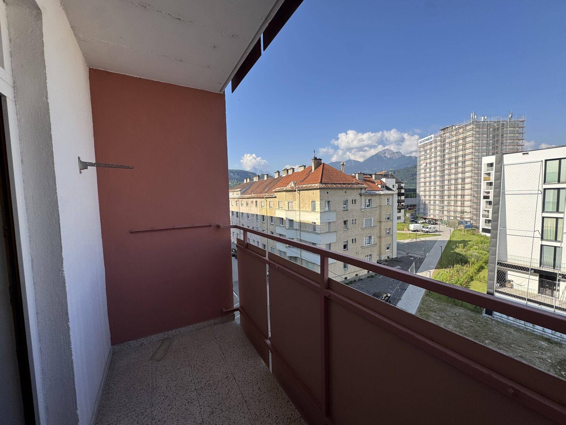 Geräumiger Balkon mit Blick auf die umliegenden Gebäude und die majestätischen Berge im Hintergrund.