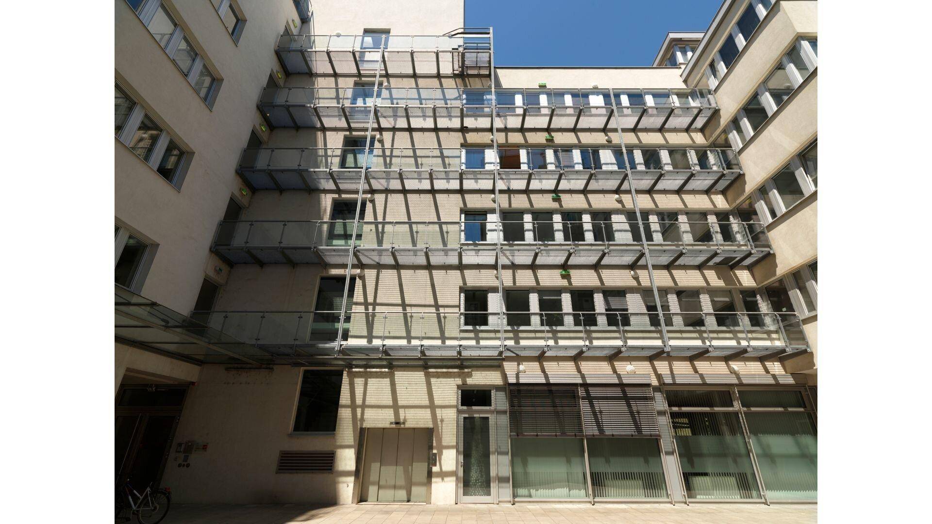 Blick in den hellen Innenhof mit mehreren Etagen und modernen Balkonkonstruktionen, die Licht hereinlassen.