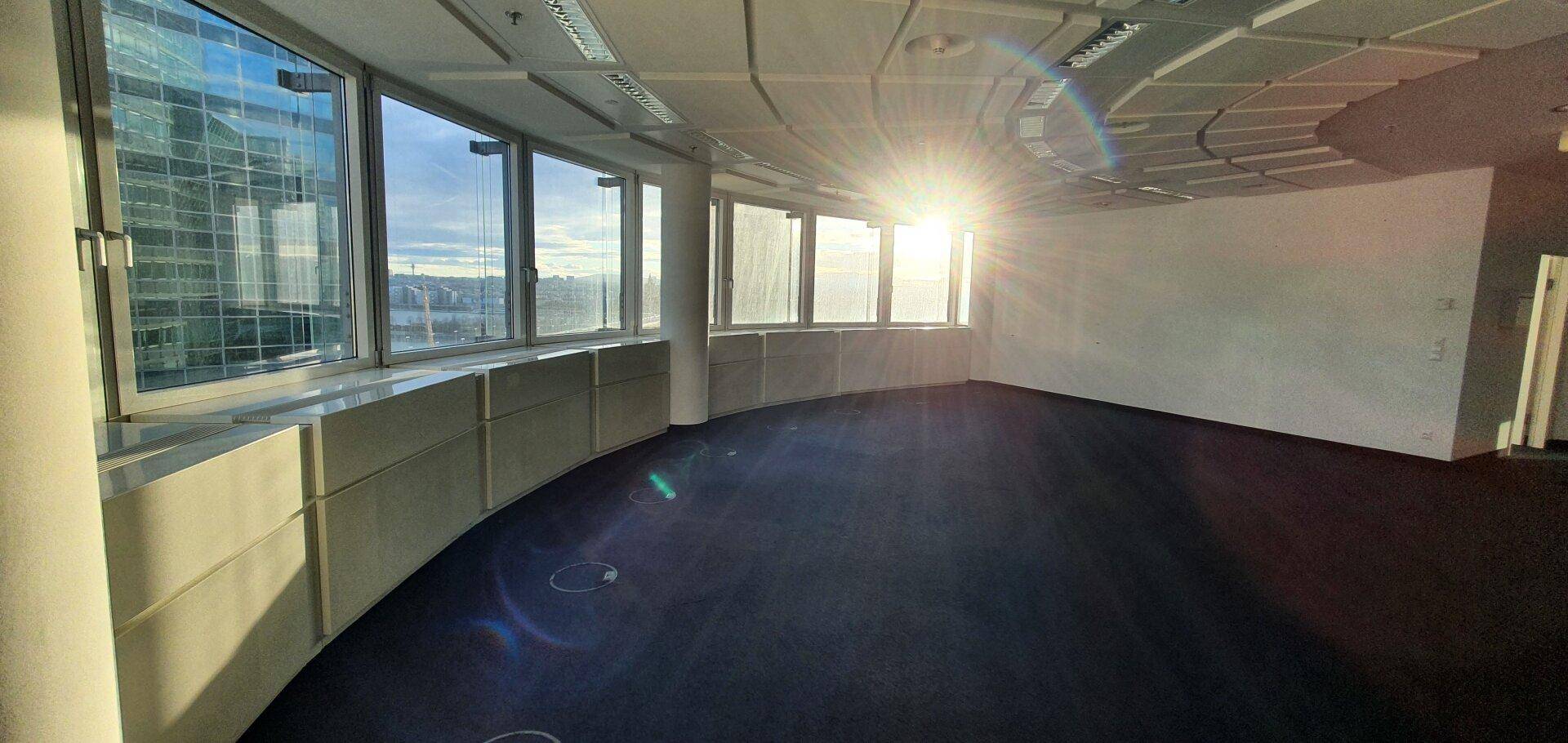 Heller Büroraum mit vielen Fenstern, die viel Tageslicht hereinlassen und eine weite Aussicht bieten.