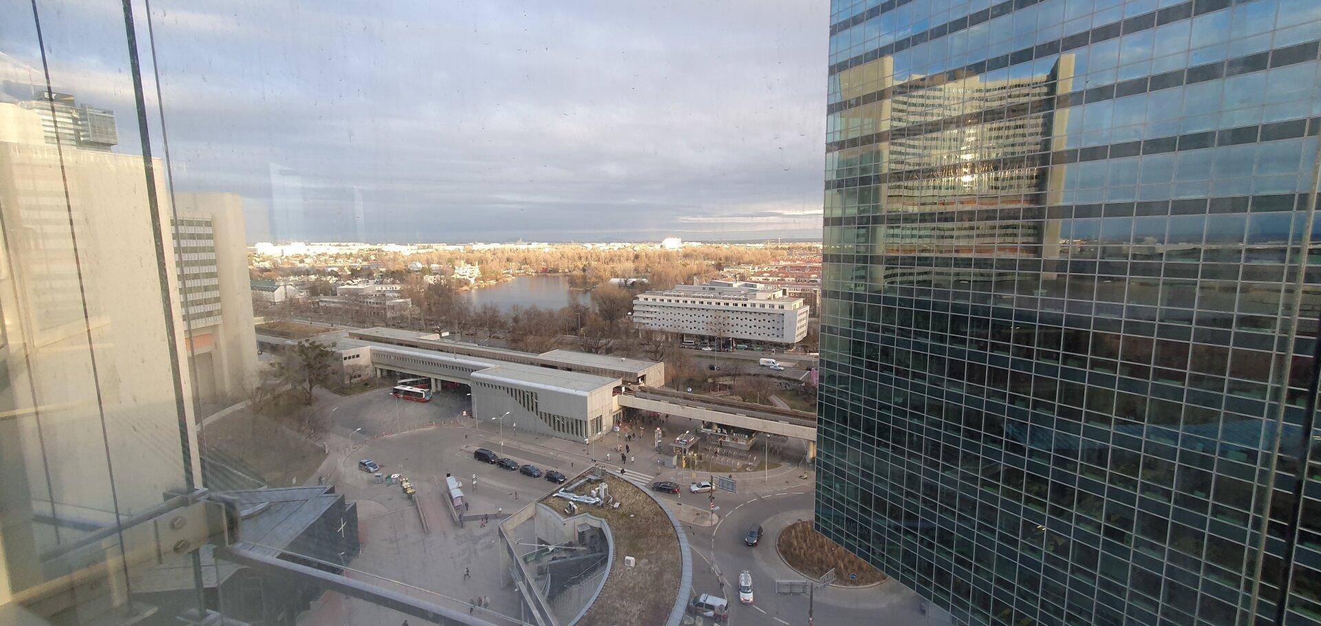 Weitblick aus einem Fenster auf die Stadtlandschaft mit einem See und umliegenden Gebäuden.
