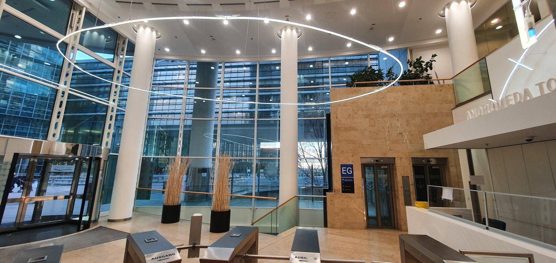 Moderne Lobby mit hohen Decken, großen Glasfassaden und eleganten Säulen im Eingangsbereich.