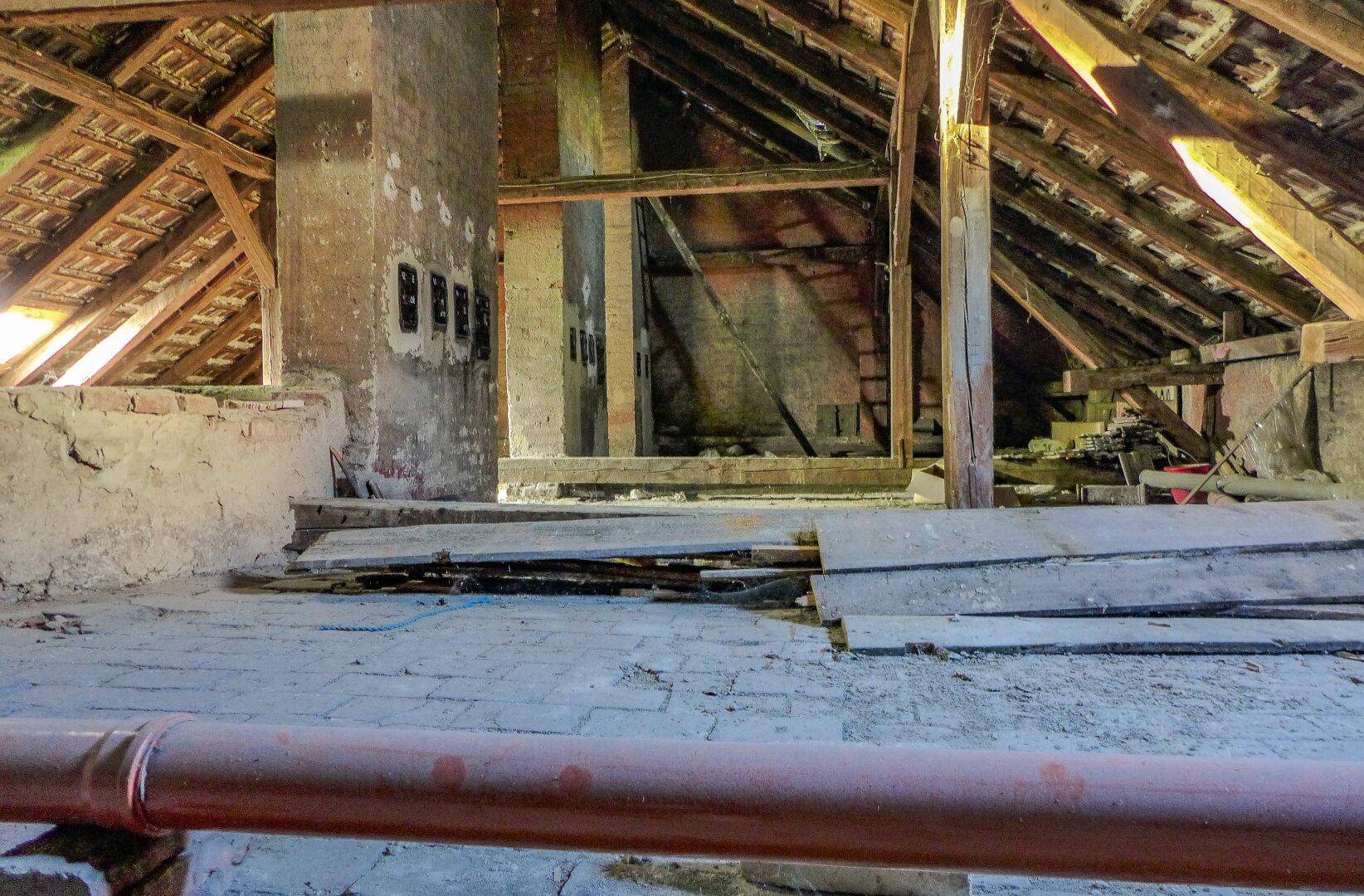 Geräumiger Dachboden mit sichtbaren Holzbalken, Ziegelwänden und viel Potenzial für Ausbau.