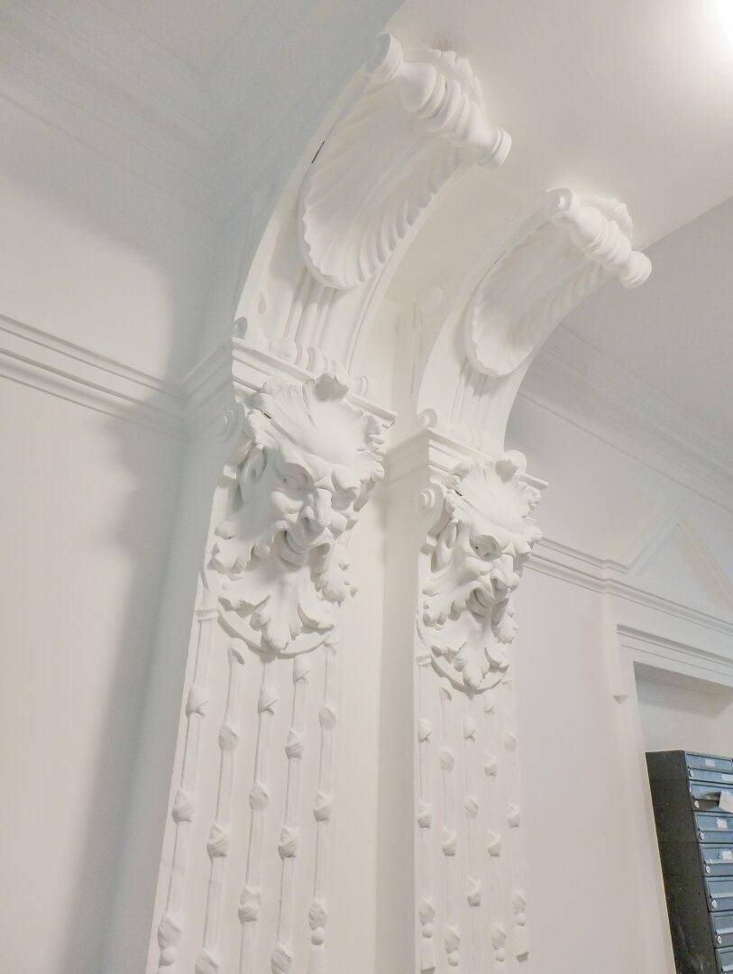 Detailaufnahme der kunstvollen Stuckverzierungen an den Säulen im historischen Eingangsbereich.