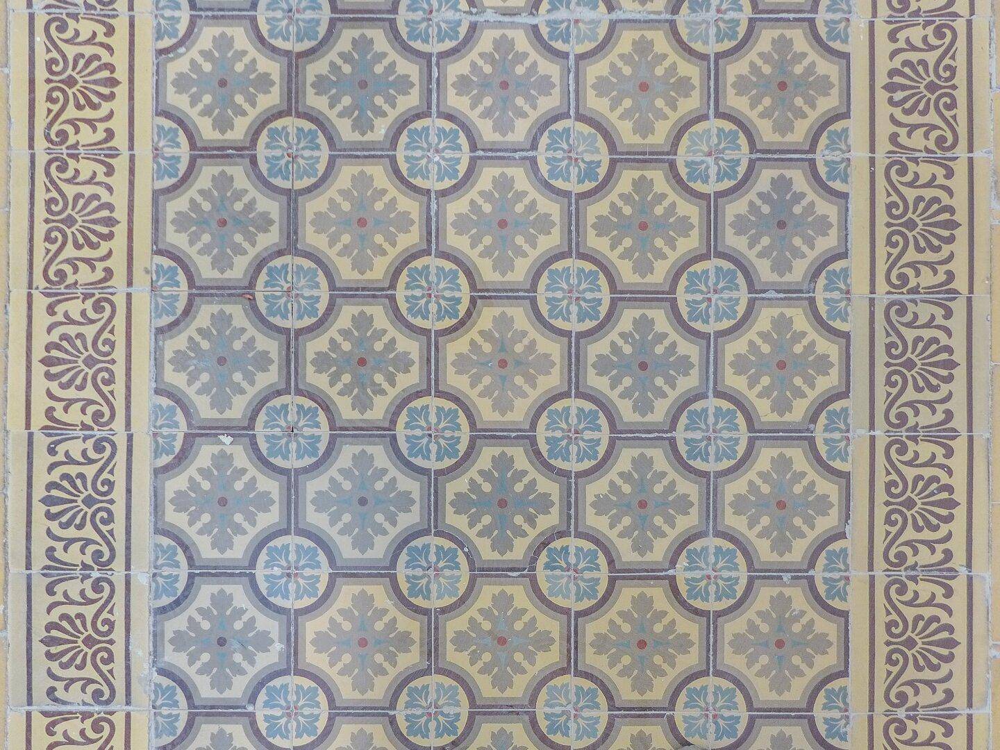 Nahaufnahme eines kunstvollen Fliesenbodens mit traditionellem Muster in Blau- und Beigetönen.