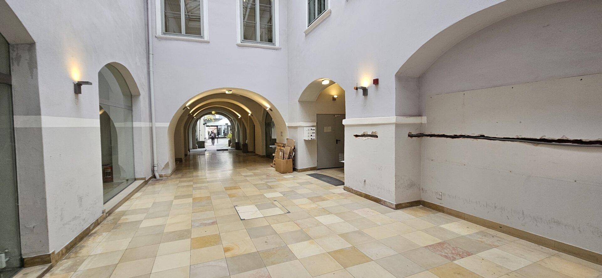 Überdachter Innenhof mit Arkaden, Fliesenboden und Zugang zu verschiedenen Bereichen, sehr charmant.