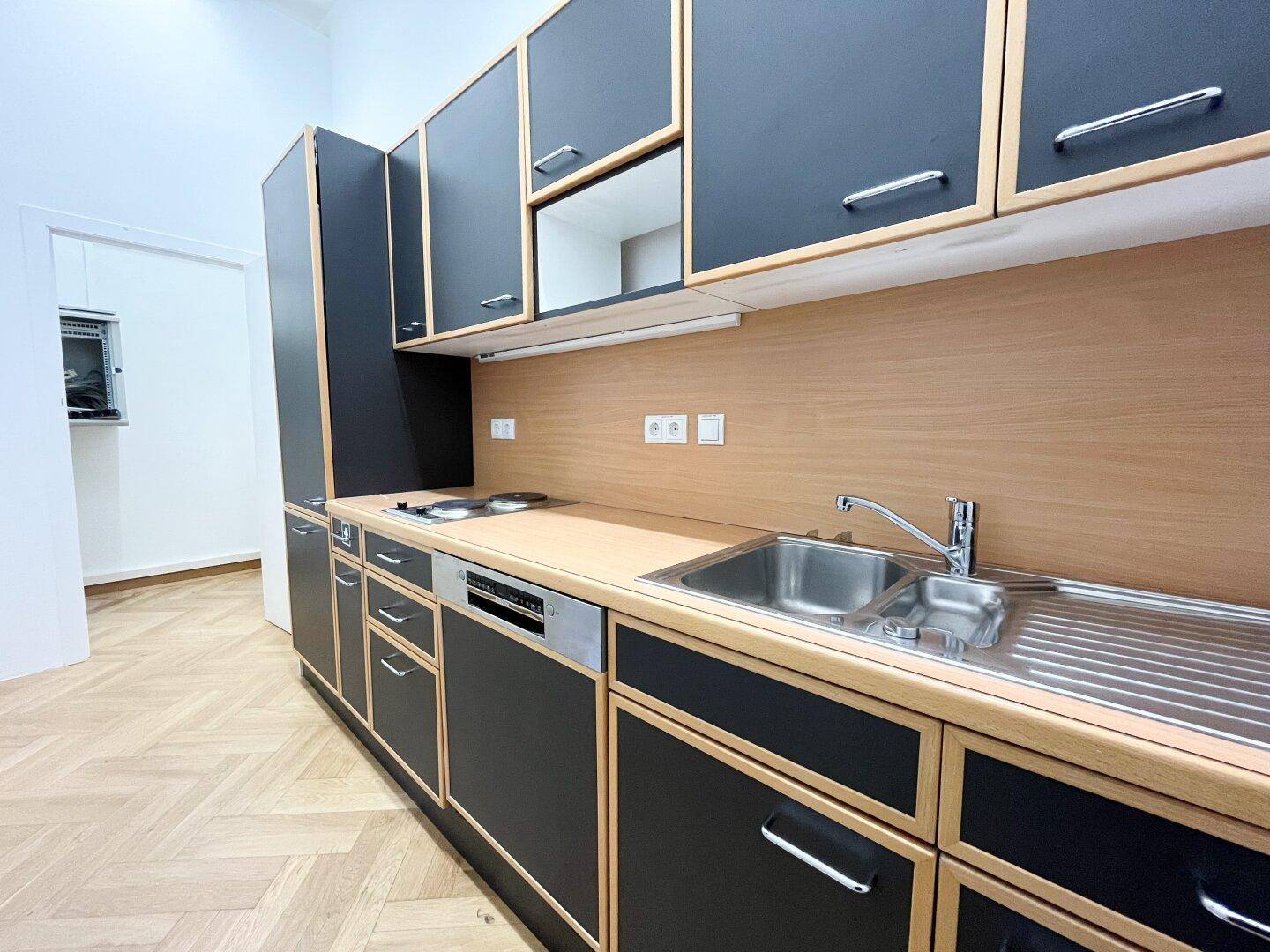 Moderne Küchenzeile mit schwarzen Schränken, Holzdetails und integrierten Geräten.