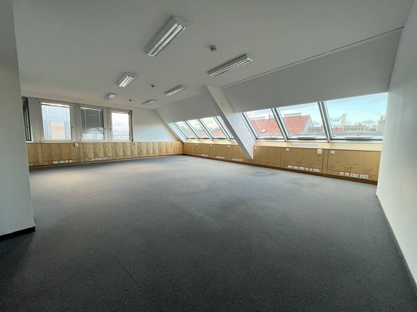 Geräumiges Büro im Dachgeschoss mit Teppichboden und großen Dachfenstern für viel Tageslicht.