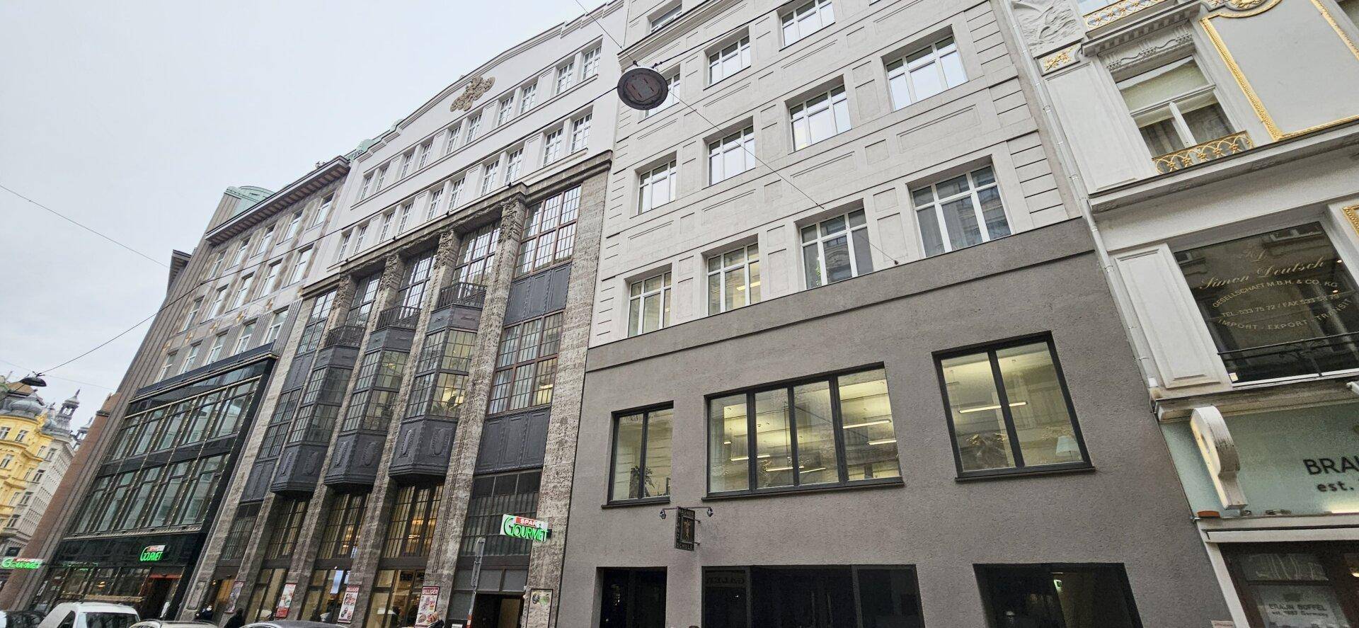 Mehrstöckiges Geschäftsgebäude mit moderner Fassade und großen Fenstern in einer städtischen Umgebung.