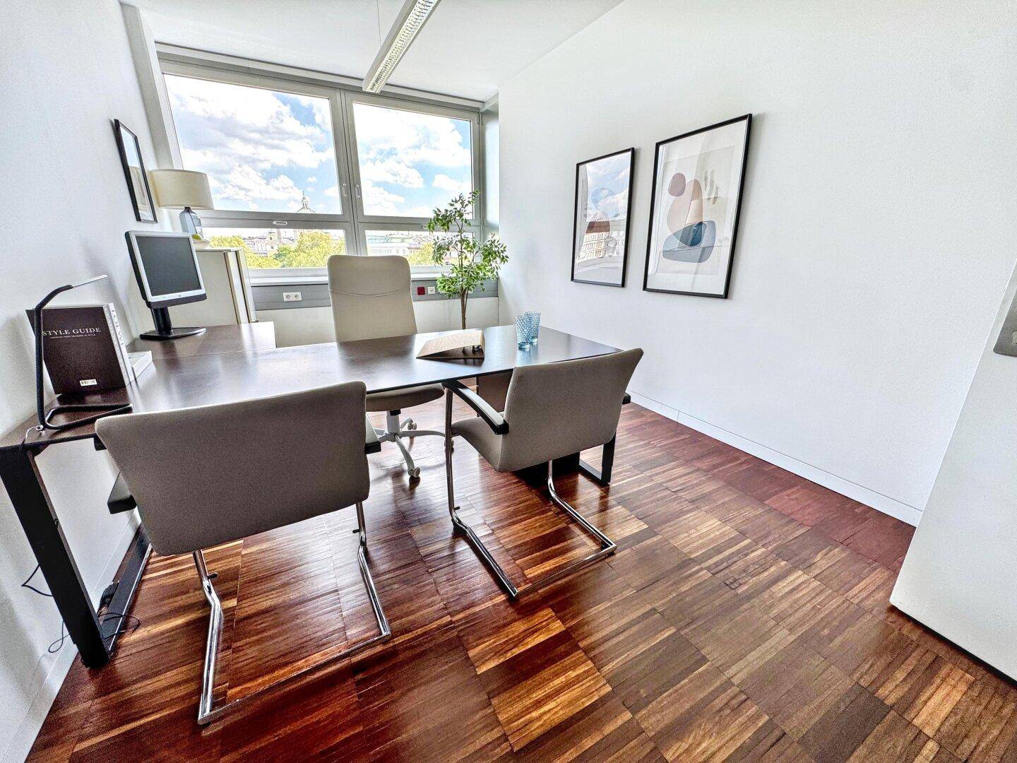 Einzelbüro mit Holzboden, großem Schreibtisch und viel Tageslicht durch die Fenster.