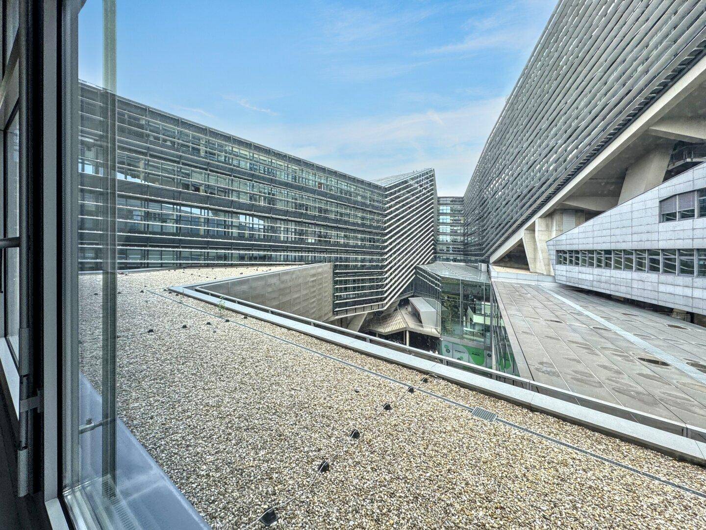 Moderne Architektur mit Glasfassaden und komplexen Gebäudestrukturen unter blauem Himmel.