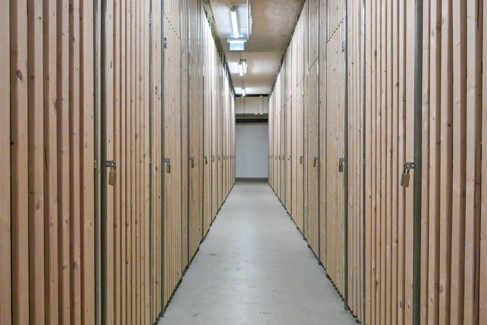 Langer Gang im Kellerbereich mit vielen individuellen Lagerabteilen aus Holz.