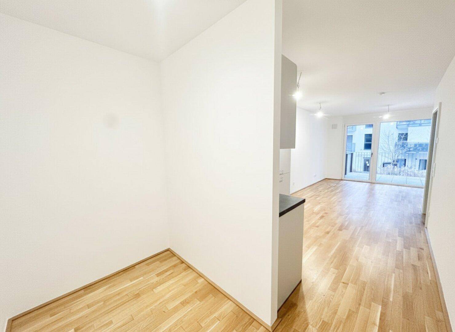 Offener Wohnbereich mit hellem Parkettboden und viel Tageslicht, ideal für flexible Einrichtung.
