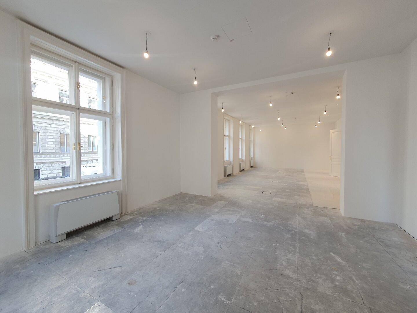 Weitläufiger Innenraum mit hohen Decken und großen Fenstern, ideal für gewerbliche Nutzung.