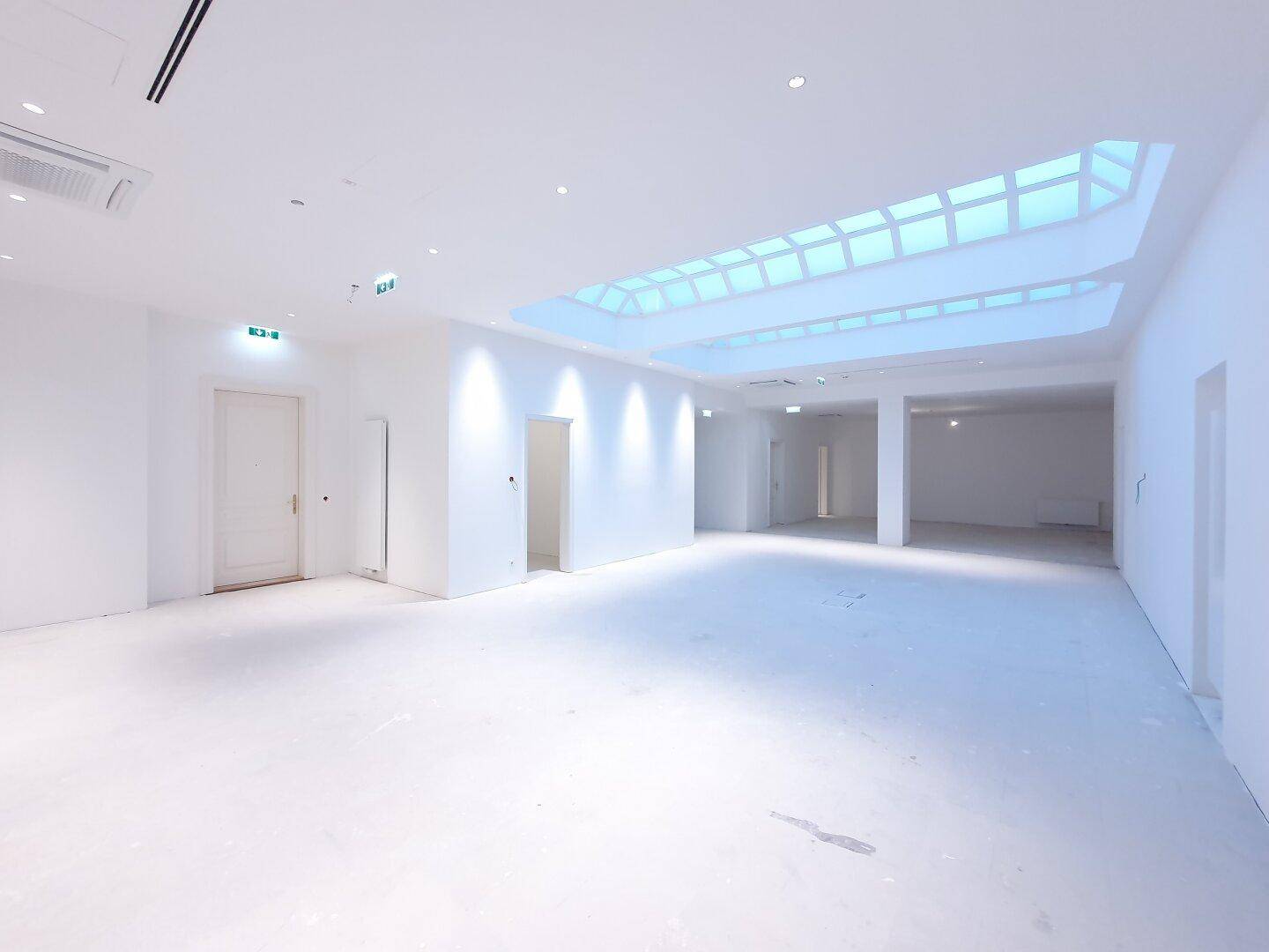 Großer, heller Empfangsbereich mit beeindruckendem Oberlicht und moderner Beleuchtung.