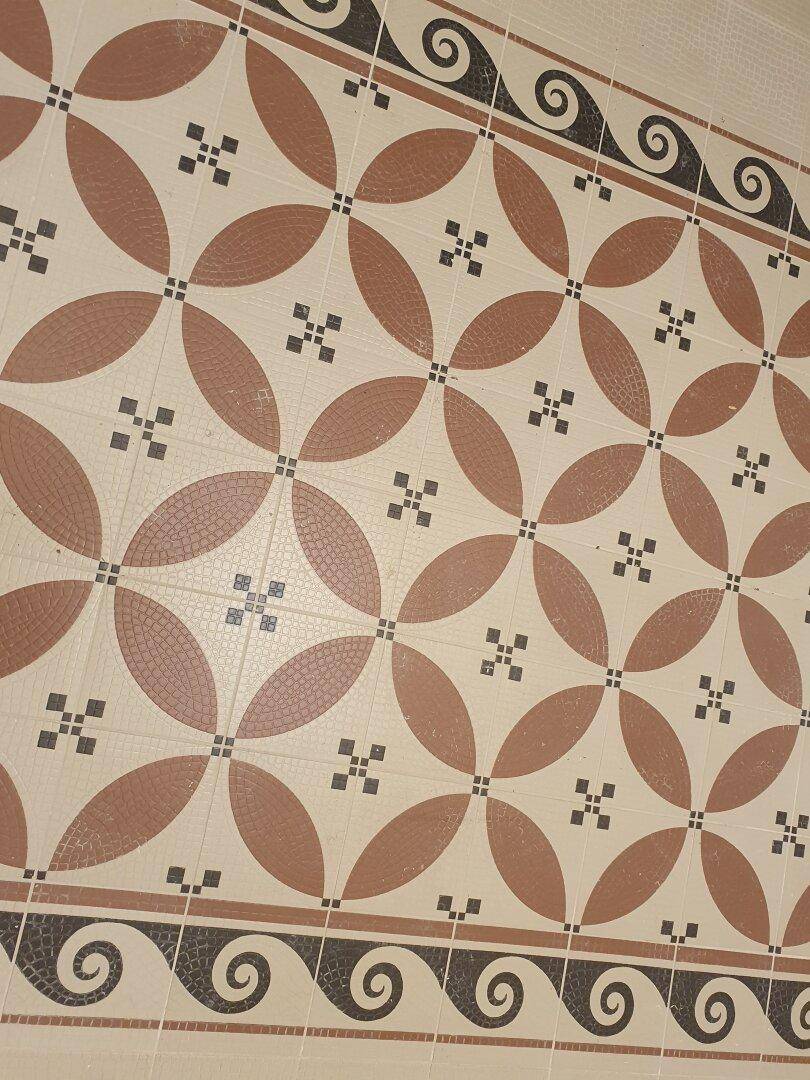 Detailaufnahme eines kunstvoll gemusterten Fliesenbodens in warmen Erdtönen.