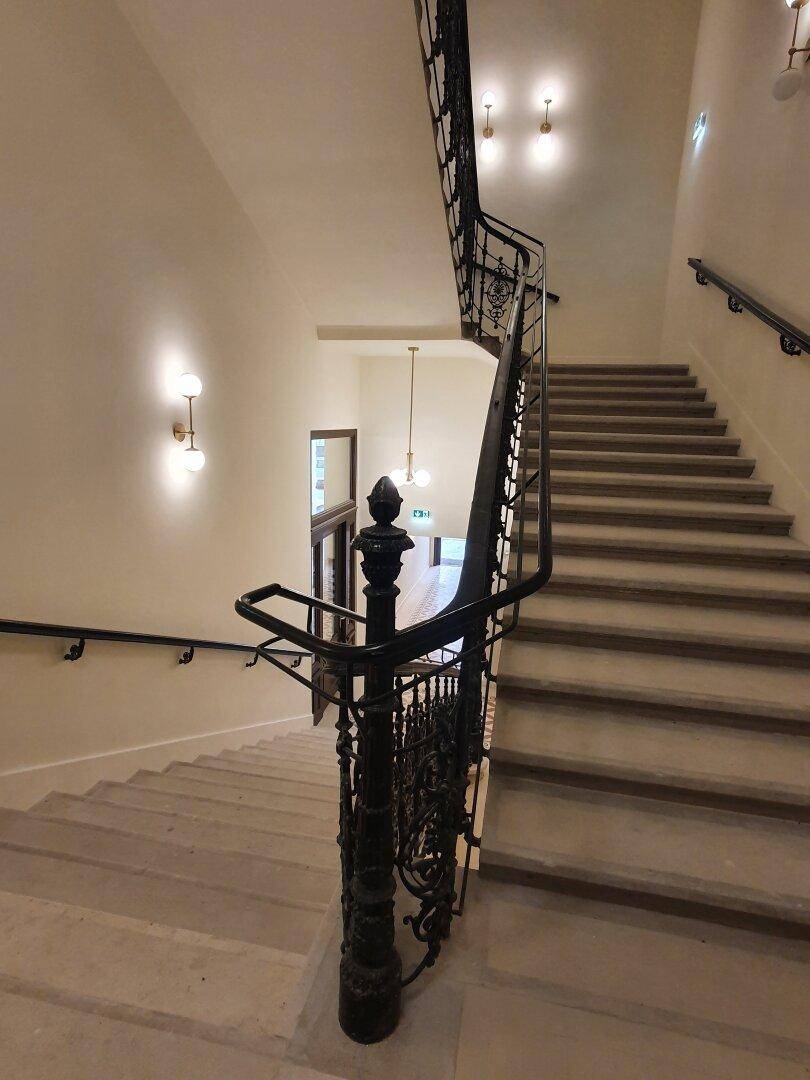 Historisches Treppenhaus mit kunstvollem schmiedeeisernem Geländer und Steinstufen.
