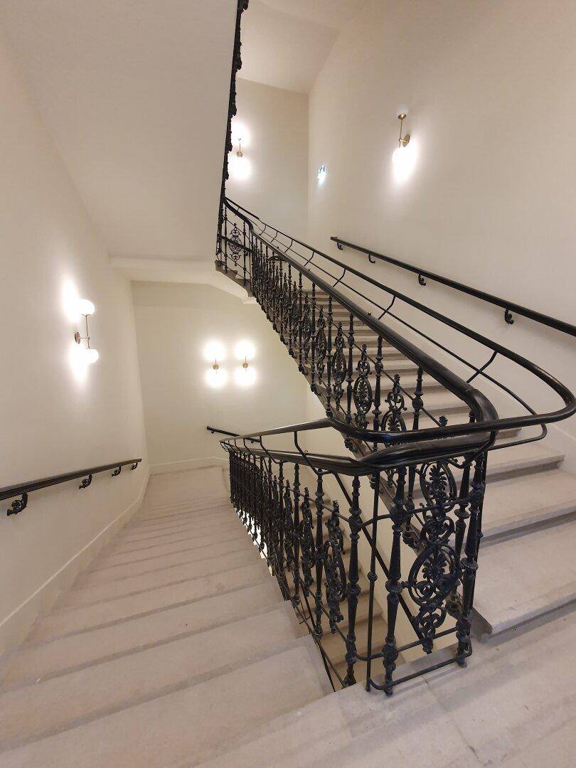 Geschwungenes Treppenhaus mit elegantem schmiedeeisernem Geländer und heller Beleuchtung.