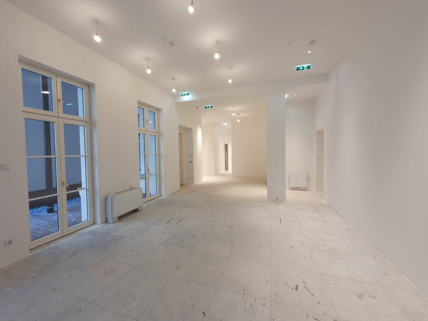 Langer, heller Flur mit mehreren Türen und großen Fenstertüren, die viel Licht hereinlassen.
