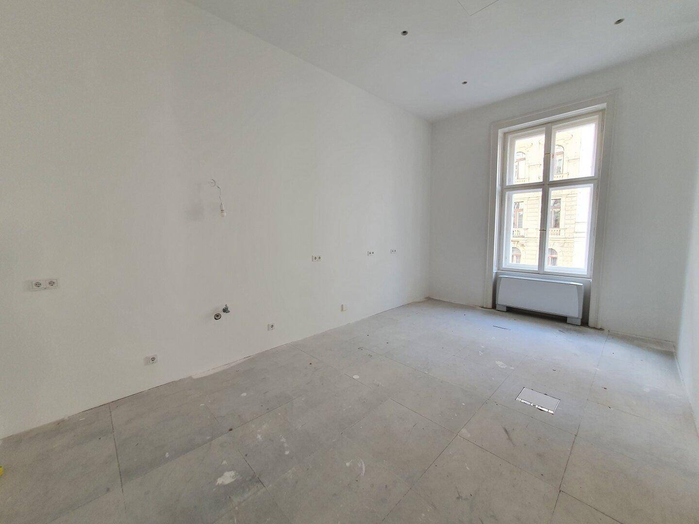Kleinerer, heller Büroraum mit einem großen Fenster und weiß gestrichenen Wänden, ideal für ein Einzelbüro.