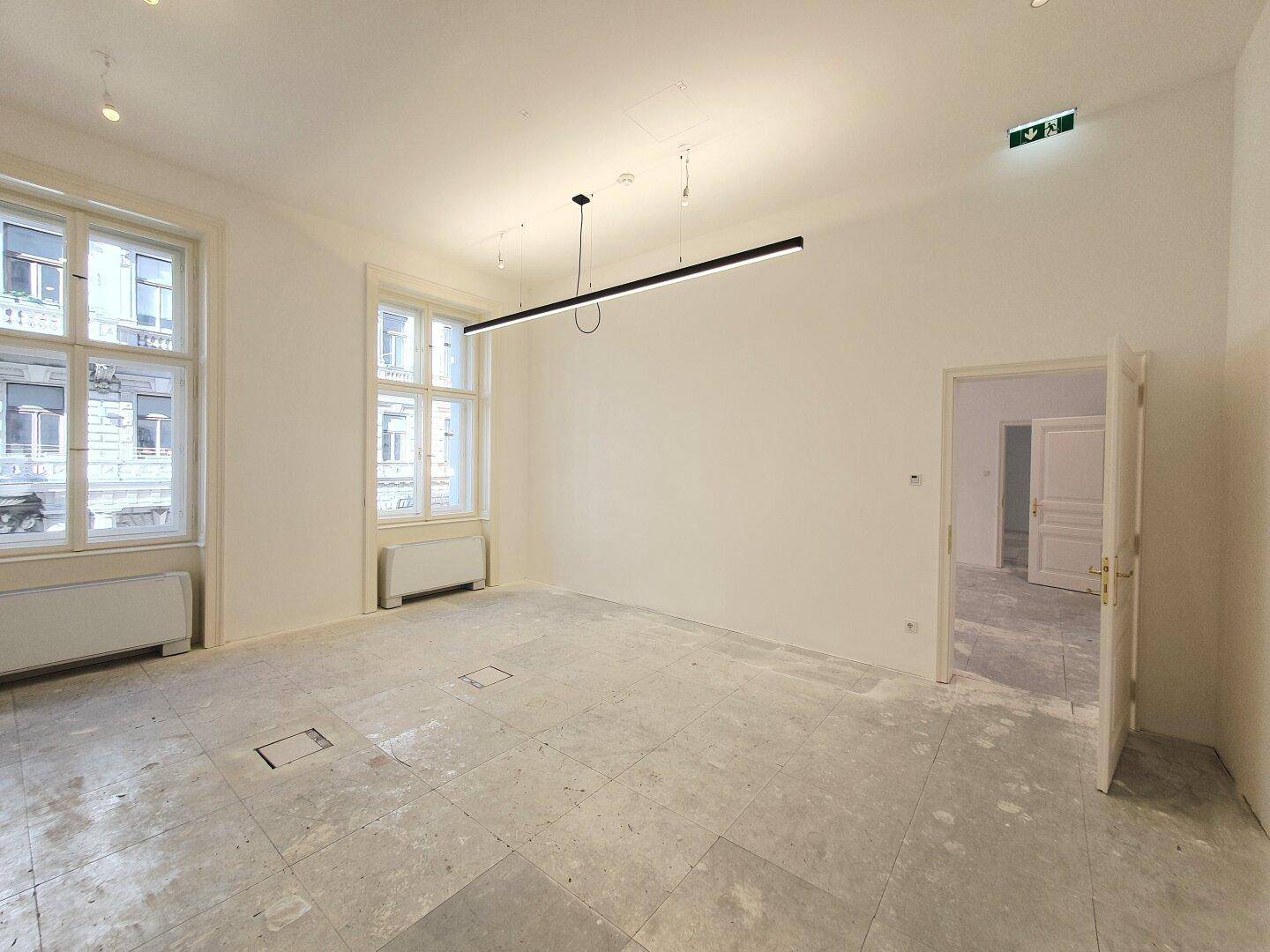 Geräumiger, heller Raum mit großen Fenstern und moderner Beleuchtung, ideal für Büros.
